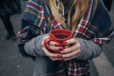 Person holding a red mug with red manicured nails